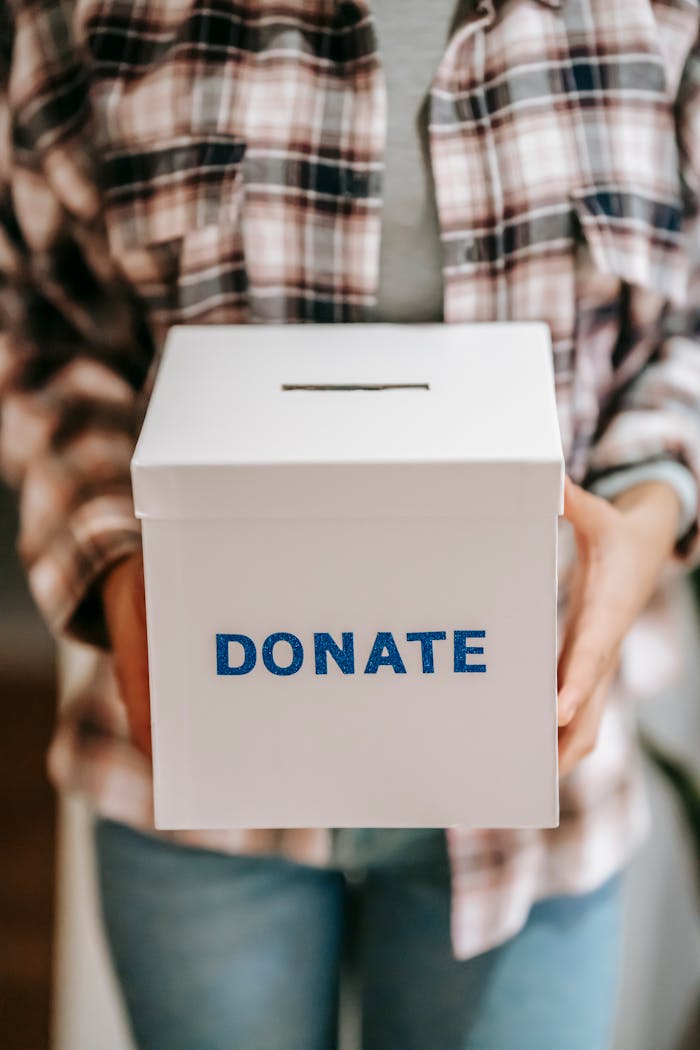 Home Close-up of a person holding a donate box, encouraging charity and support.