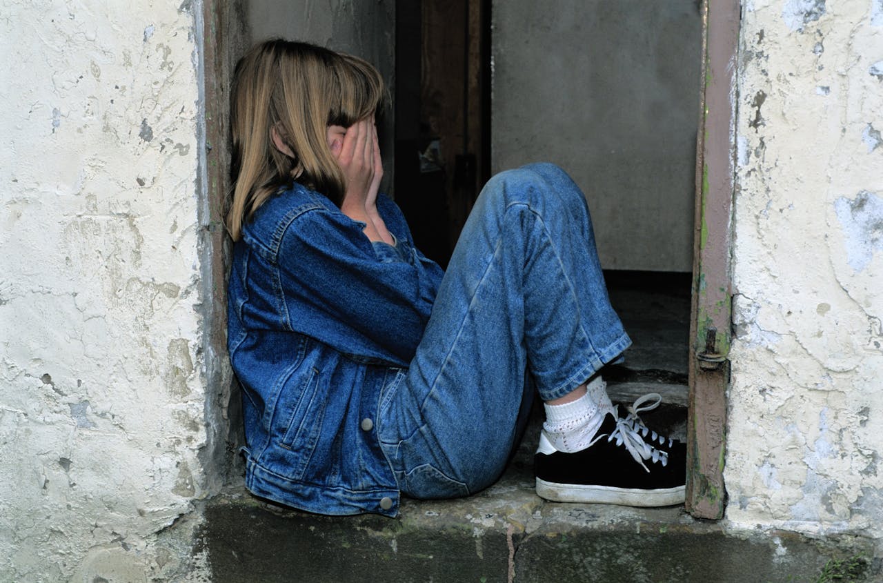 The Art of Drawing Readers In: Your attractive post title goes here A young girl in denim sits alone in a doorway looking distressed, conveying loneliness.